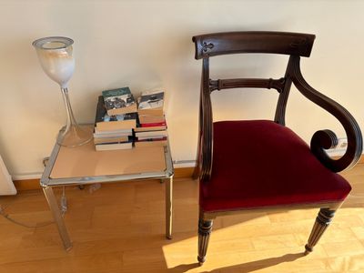 a red chair sitting next to a table with a lamp on top of it