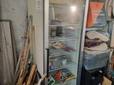 une photo d'un réfrigérateur dans un garage où règne un grand désordre