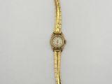 gros plan d'une montre-bracelet en or sur une surface blanche