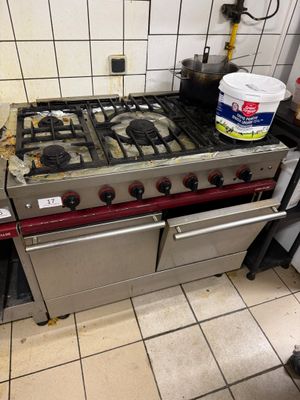 a stove that is sitting in a kitchen with a bucket of paint on it