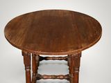 an old wooden table with a round top and turned legs