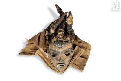un masque marron orné de cornes, posé sur un fond blanc