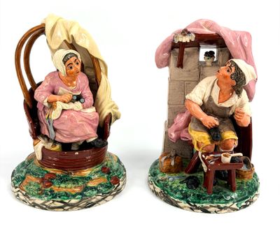 pair of ceramic figurines of a woman and a man sitting in a chair