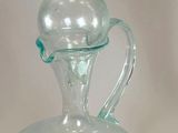 a clear glass bottle with a green handle on a table