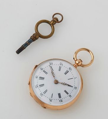 a gold pocket watch and a key on a white table