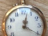 a close up of a pocket watch on a wooden table