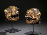 a pair of carved masks on stands with a black background