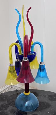Des vases en verre aux couleurs vives sont disposés sur une table devant un miroir