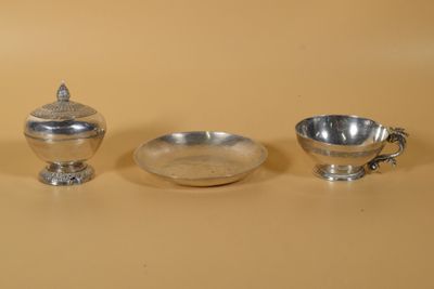 trois objets en argent posés sur une table, à côté d'un bol et d'une tasse