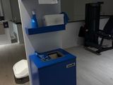 une photo d'une salle de sport avec une armoire bleue et des toilettes blanches
