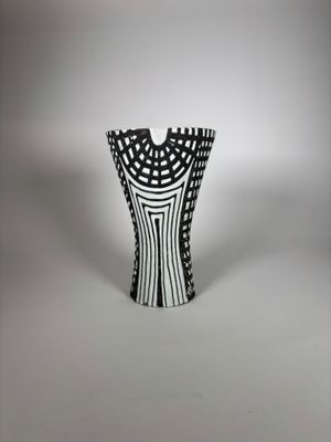 un vase noir et blanc posé sur une surface blanche