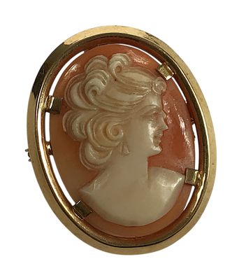 Une broche de couleur dorée représente le profil d'une femme.