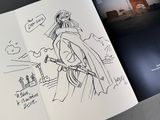 an open book with a drawing of a woman holding a sword