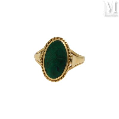 gros plan d'une bague en or avec une pierre verte