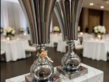 two silver vases sitting on top of a marble table