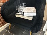 a black chair with a stack of books on it in front of a brick wall