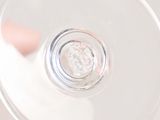 someone holding a wine glass in their hand with a coin in it