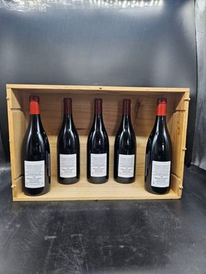 quatre bouteilles de vin rouge dans un coffret en bois posé sur une table