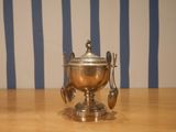 a silver bowl with spoons and spoons on a wooden table