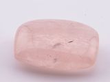 une pierre de quartz rose posée sur une surface blanche