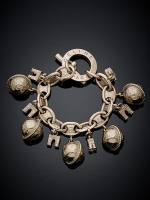 un gros plan d'un bracelet en argent orné de breloques, sur fond noir