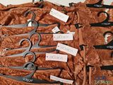 six pairs of scissors with tags on them sitting on a table