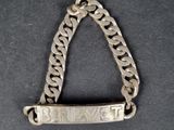 un gros plan sur un bracelet à chaîne en argent sur lequel est inscrit le mot « believe »