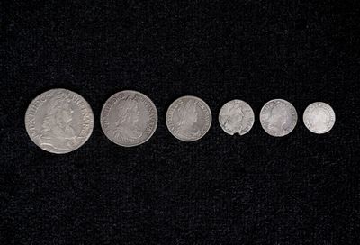 several silver coins are arranged in a row on a black surface
