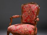 une chaise rouge et dorée dont l'assise est recouverte d'un tissu à motifs floraux