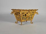 une jardinière ancienne en laiton, ornée de sculptures élaborées, posée sur un socle
