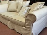 a white couch with many pillows on it in a room