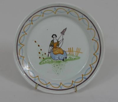 une petite assiette sur laquelle est représentée une femme assise par terre