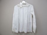 the white blouse is hanging on a hanger on the wall