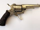 un vieux revolver avec une poignée en bois sur une surface blanche
