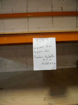 une pancarte posée sur une étagère dans une pièce aux murs de briques