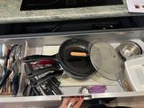 un tiroir rempli d'ustensiles de cuisine et de casseroles
