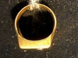 a gold ring with a knot around it on a black surface