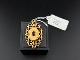 a close up of a gold plated pendant on a black surface