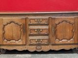 un vieux buffet en bois posé à même le sol, près d'un mur rouge