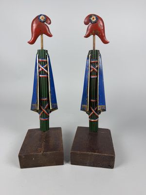 two wooden sculptures of a bird and a bird on a wooden stand