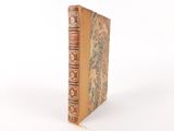 an old book sitting on top of a white table next to a white wall