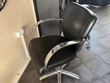 a black chair in a salon with a mirror on the wall