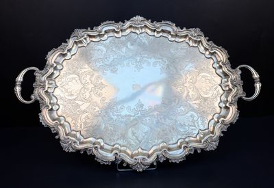 un plateau en argent richement décoré, muni de poignées, sur fond noir