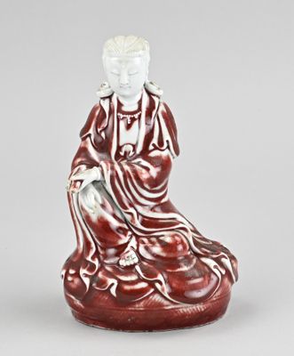 une figurine rouge et blanche représentant un homme assis sur un rocher