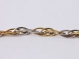 a close up of a gold and silver chain on a white surface