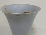 a gray vase with a yellow handle on a white floor