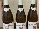 three bottles of wine sitting on top of a wooden barrel