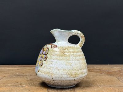 un petit vase blanc posé sur une table en bois