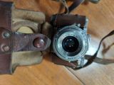 an old camera with a leather case on a table