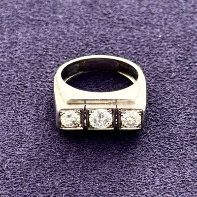 a close up of a ring with three diamonds on a purple surface